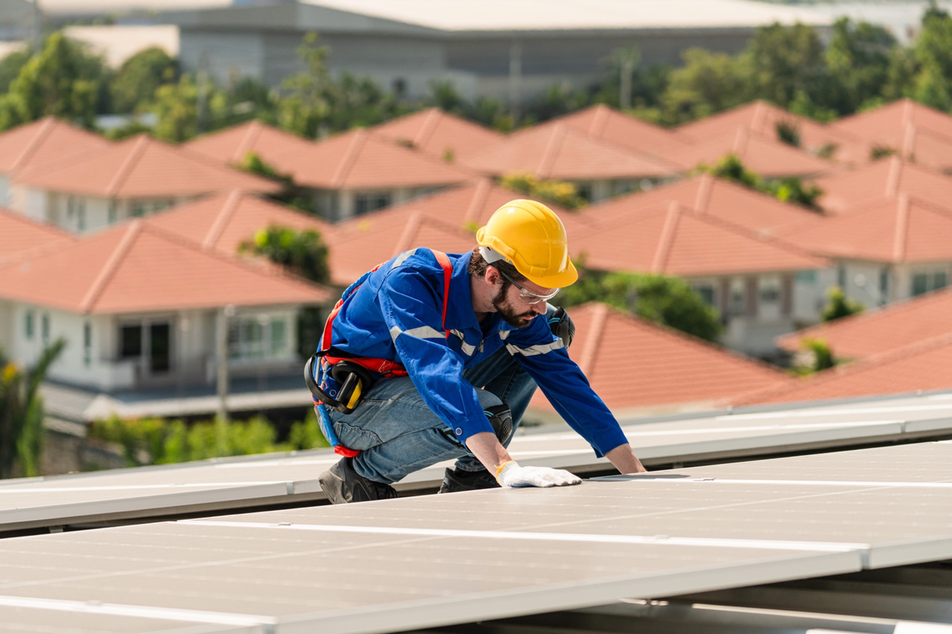 A Man Wearing Yellow Hard Hat and Blue Uniform Working on a Roof